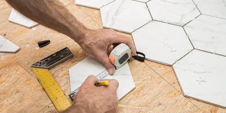 Interior finishing worker (tiler) laying white hexagon ceramic gres tiles on the floor. Bathroom renovation works. Handyman at work.